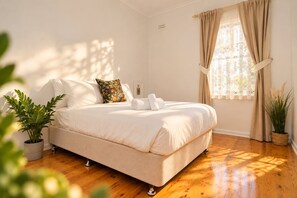 Ein Schlafzimmer mit einem Bett, einem Fenster mit Vorhängen und einer Zimmerpflanze.