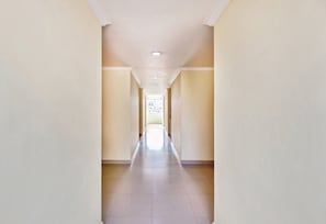 A long, narrow hallway with a tiled floor and plain walls. - Hotel O Qualia Pride Financial District (Hyderabad)