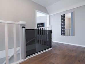 A modern interior with a white railing, a glass door, and a wall-mounted height chart. - Luxury villa with private wellness (Colijnsplaat)
