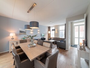 A modern living room with a dining area, a sofa set, and a TV. - Luxury villa with private wellness (Colijnsplaat)