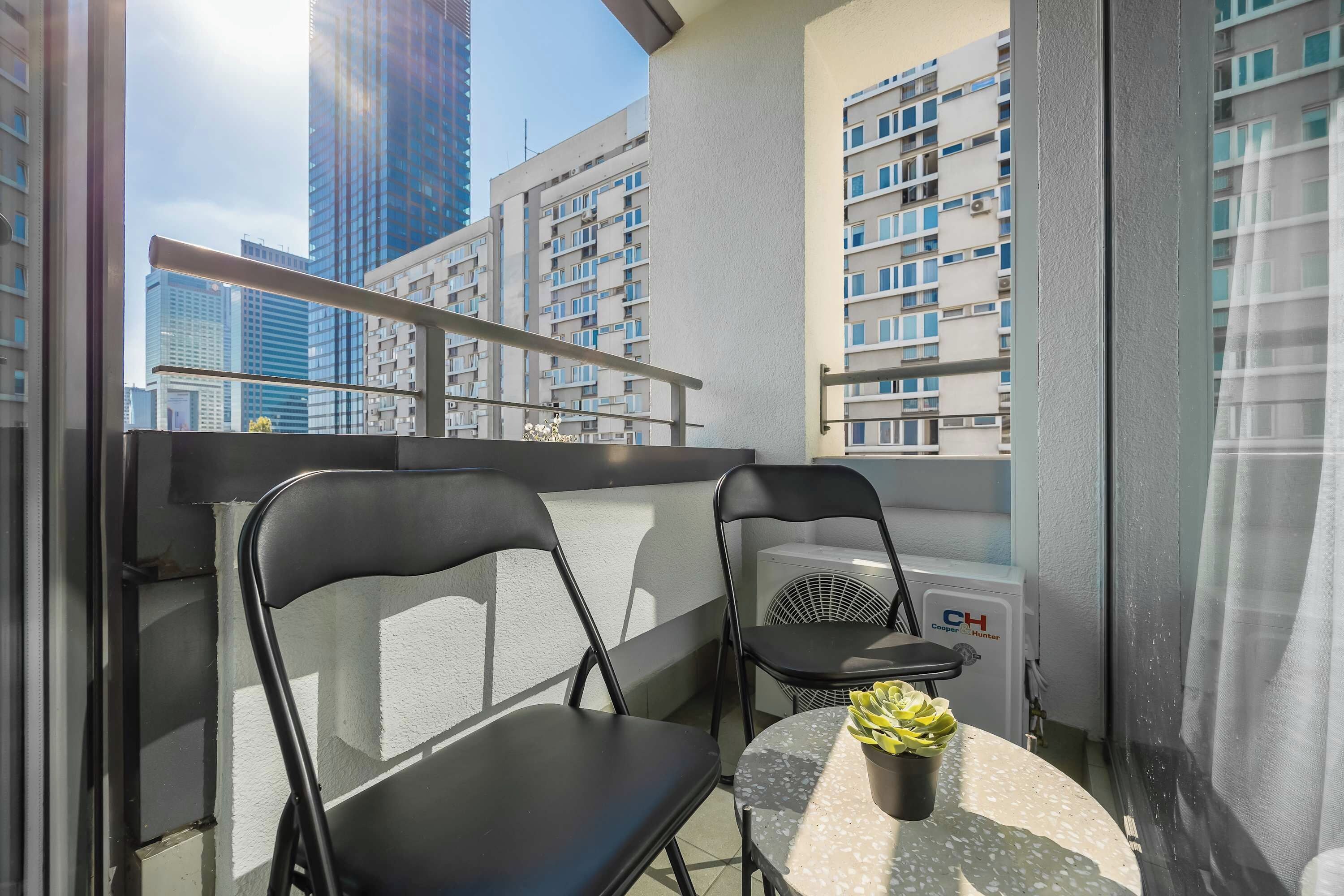 A balcony with two chairs, a small table, and a potted plant.