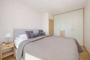 Un dormitorio con cama, mesita de noche, lámpara y armario.