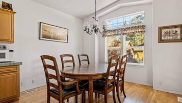 Un espace repas avec une table ronde et des chaises en bois, un lustre et des œuvres d’art accrochées aux murs.