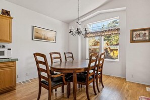 Un espace repas avec une table ronde et des chaises en bois, un lustre et des œuvres d’art accrochées aux murs.