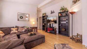 Een moderne woonkamer met een modulaire bank, een flatscreen televisie en een boekenplank.