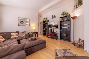 Een moderne woonkamer met een modulaire bank, een flatscreen televisie en een boekenplank.