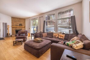 A living room with a fireplace, a large sectional sofa, a leather armchair, and a wooden coffee table. - Private Hot Tub + Fireplace, 5 Min to Slopes, Fenced Yard, Sleeps 8 (Big Bear)