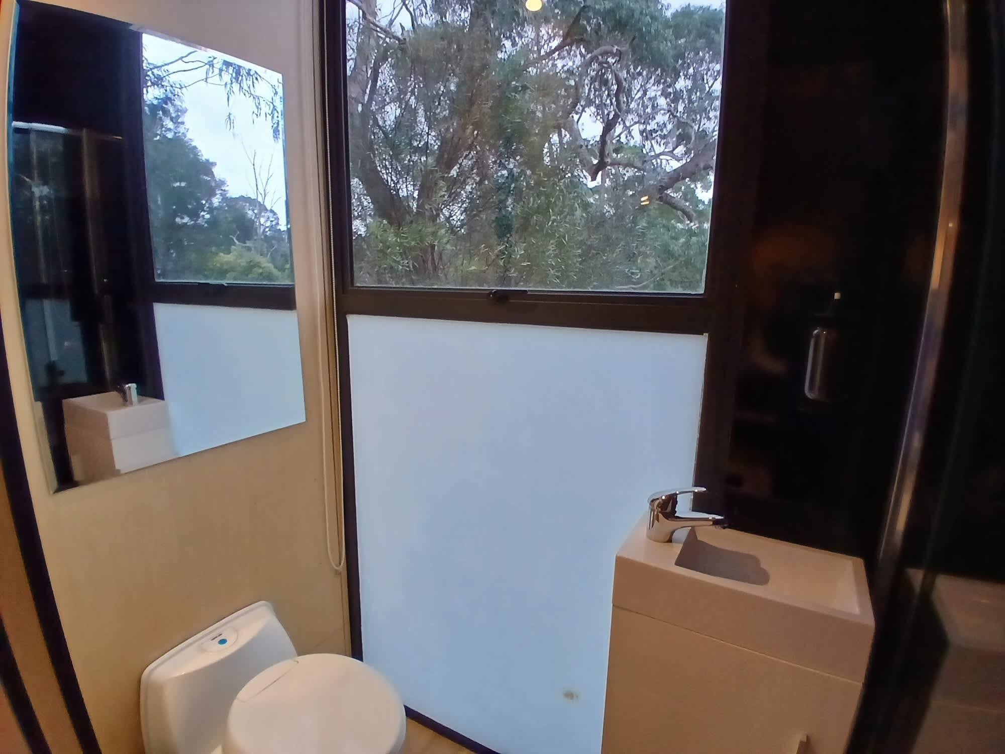 A small bathroom with a toilet, sink, and a mirror.