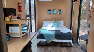 Ein modernes Schlafzimmer mit Bett, Nachttisch und Blick ins Freie.