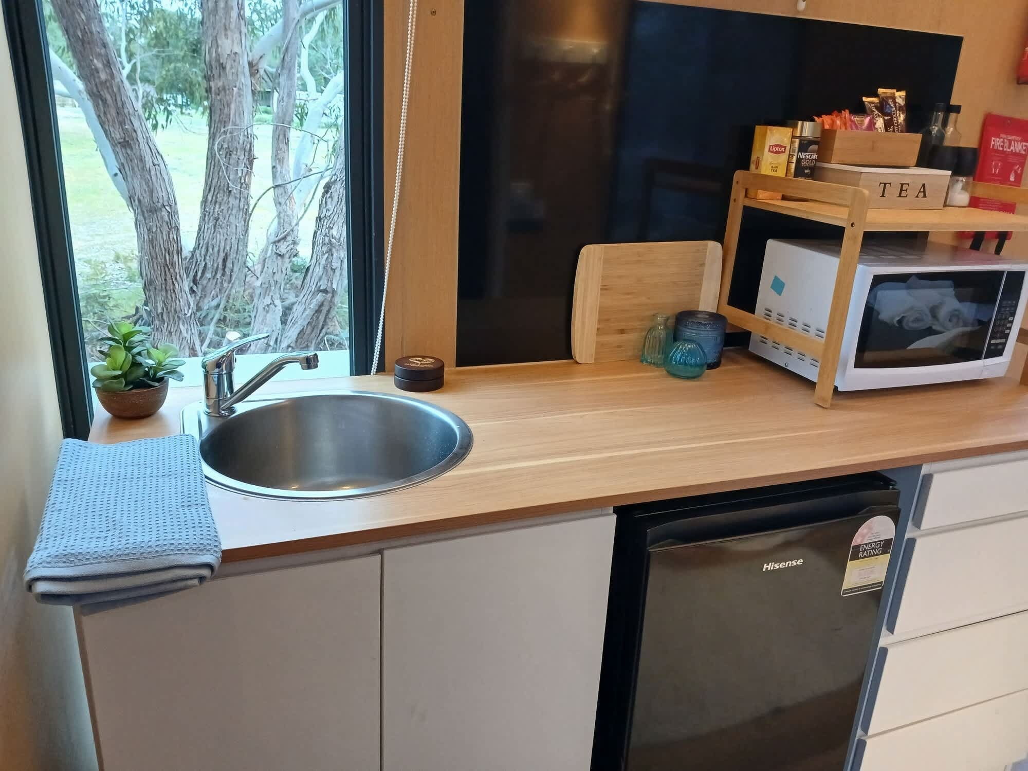 Une cuisine compacte équipée d’un évier, d’un four à micro-ondes et d’un petit placard.