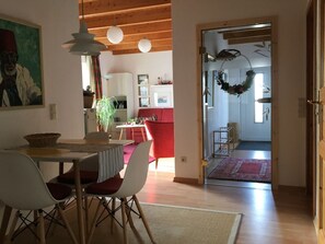 A dining area with a table and chairs, a red sofa, and a wooden ceiling. - Holiday Apartment With 1 Bedroom (Wunstorf)