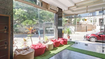 Een hotel lobby met grote ramen, kamerplanten en rode zitzakken.