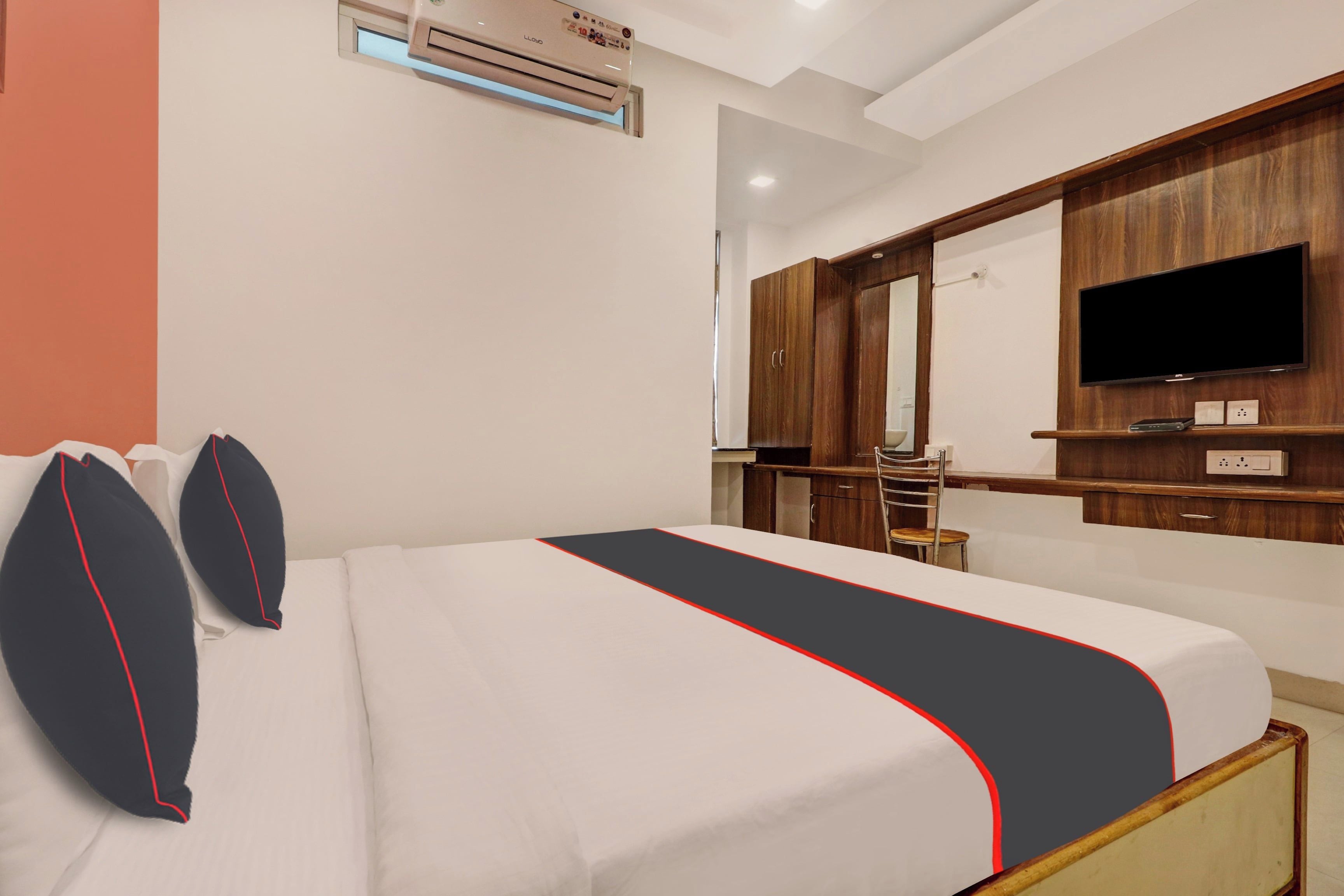 Een hotelkamer met een bed, een televisie, een kledingkast en een airconditioning.