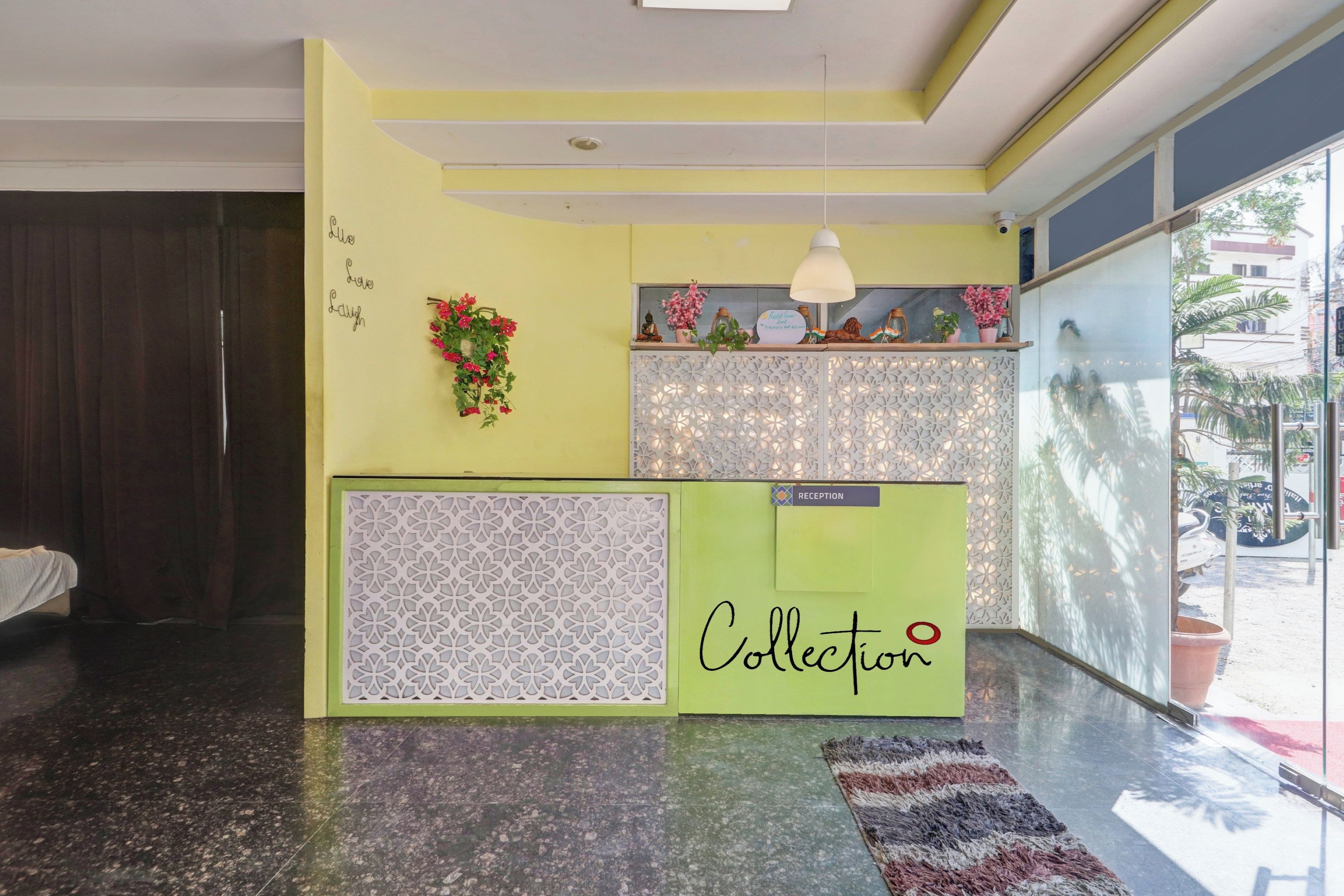 A reception area with a reception desk, a decorative wall, and a view of the outside.