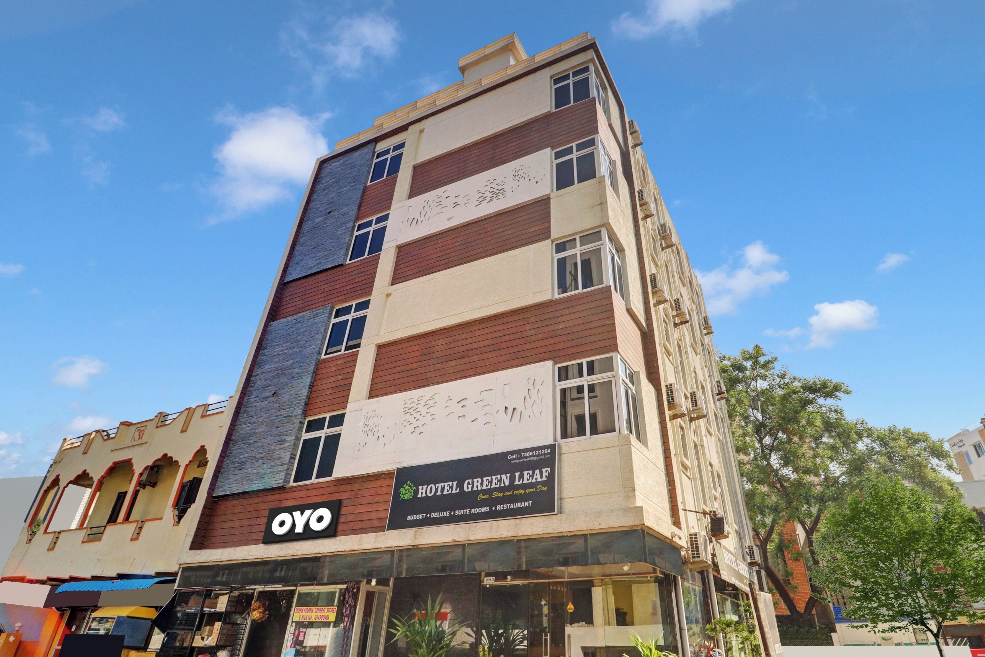 Een meerhoog hotel met een bordje waarop 'HOTEL GREEN LEAF' en 'OYO' staat.