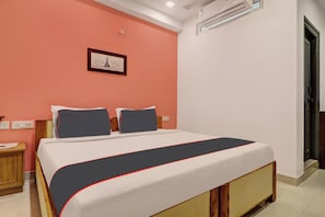 A bedroom with a bed, a nightstand, a wall-mounted air conditioner, and a door. - Capital O Qualia Gachibowli (Hyderabad)