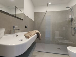 Ein modernes Badezimmer mit einem großen Waschbecken, einer Duschkabine aus Glas und einer Toilette.