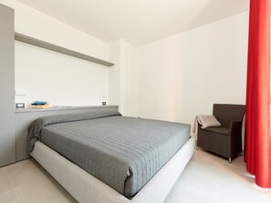 Ein modernes Schlafzimmer mit einem Bett, einem Sessel und einem roten Vorhang.