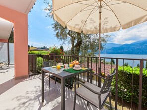 Ein Balkon mit Frühstückstisch, der Blick auf einen See und Berge freigibt.
