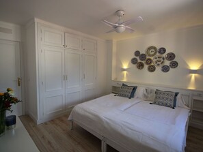 A bedroom with a bed, white wardrobe, ceiling fan, wall-mounted lights, and decorative plates. - Holiday Apartment With 1 Bedroom (Capdepera)