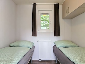 A small room with two single beds, a window with curtains, a radiator, and a cabinet. - Cottage in Oostkapelle With Swimming Pool (Oostkapelle)
