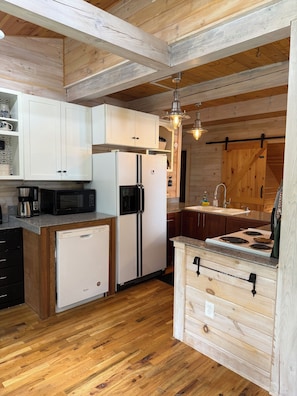 Une cuisine avec des meubles de rangement en bois, un réfrigérateur, un four à micro-ondes, une cuisinière et un évier.