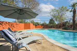 Una piscina con sillas de descanso y una sombrilla.