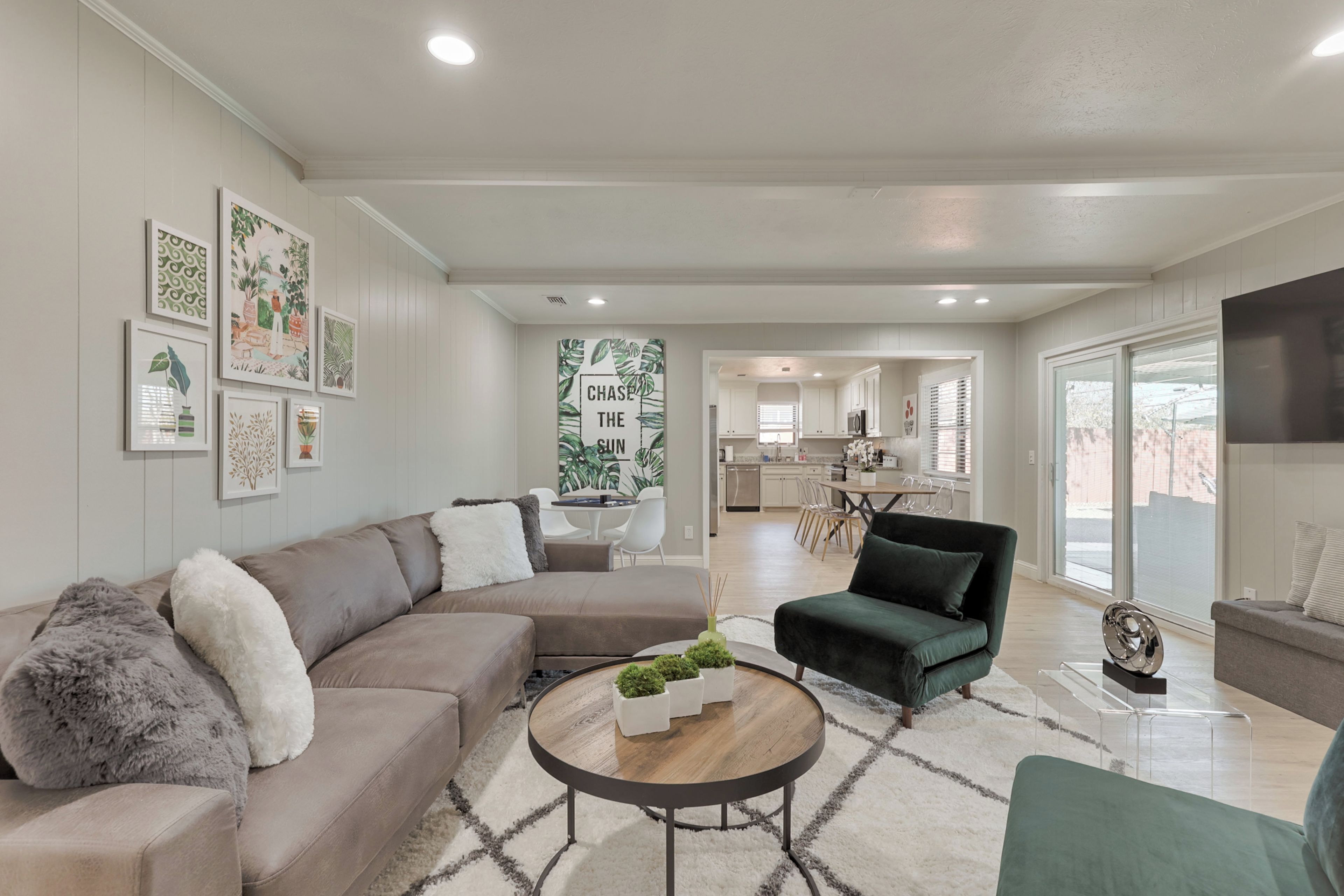 A modern living room with a sectional sofa, a round coffee table, and a green armchair.