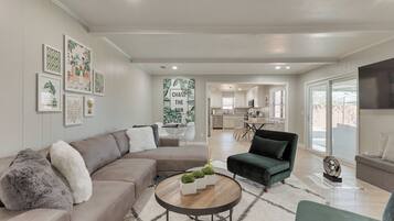 A modern living room with a sectional sofa, a round coffee table, and a green armchair.