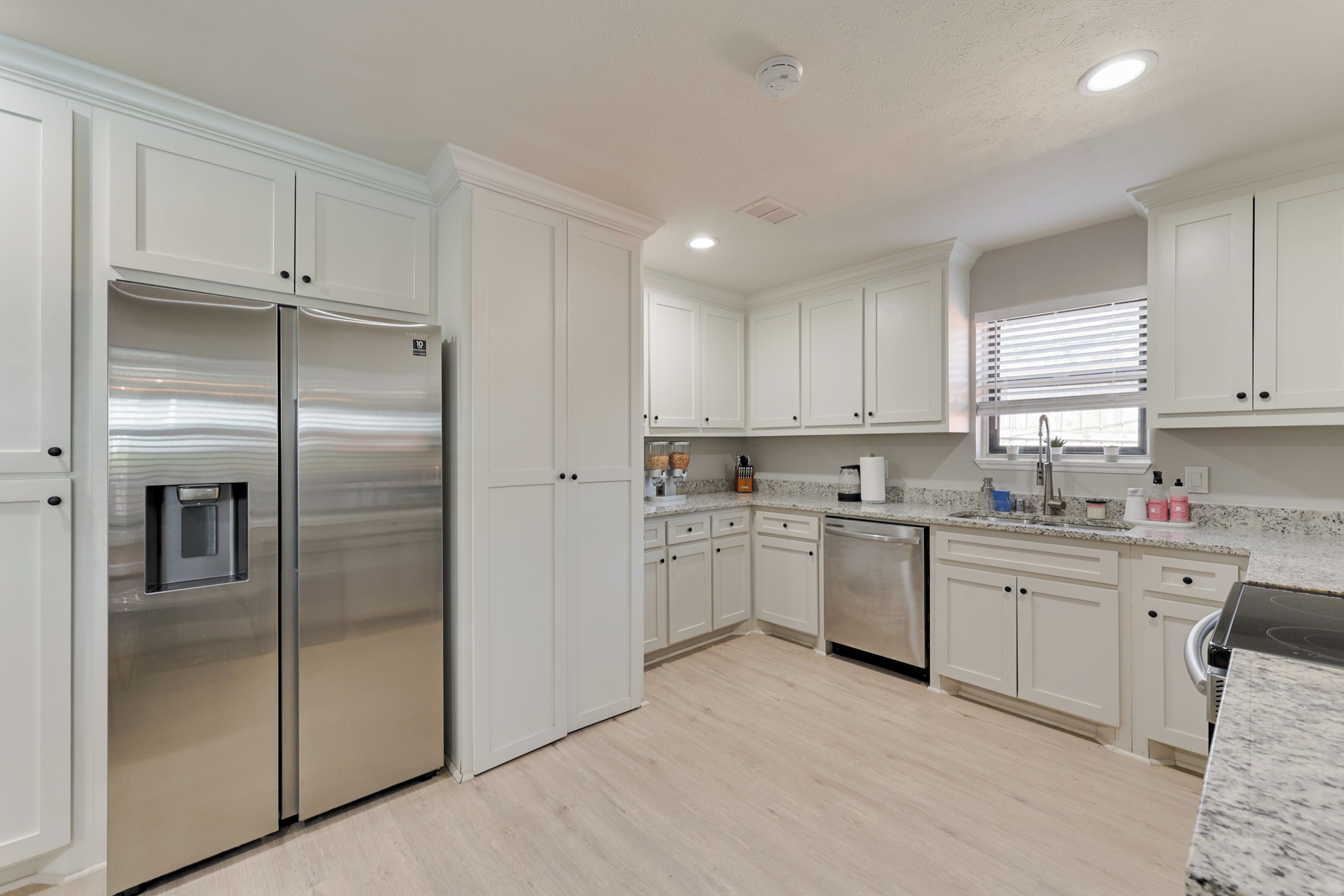 A modern kitchen with white cabinetry, stainless steel appliances, and a granite countertop.