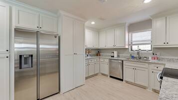 A modern kitchen with white cabinetry, stainless steel appliances, and a granite countertop.