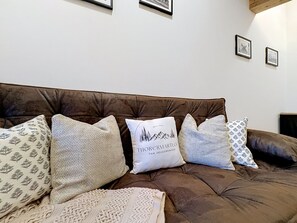 A brown sofa with multiple cushions and a knitted throw. - Thorermartlgut incl. Gästekarte by Interhome (Saalfelden am Steinernen Meer)