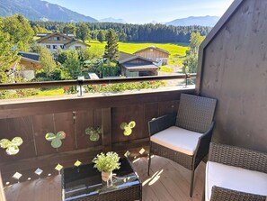 Ein Balkon mit Korbmöbeln, einem kleinen Tisch und einem Blumentopf.