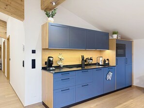A modern kitchen with blue cabinets, a wooden countertop, and a built-in oven. - Thorermartlgut incl. Gästekarte by Interhome (Saalfelden am Steinernen Meer)