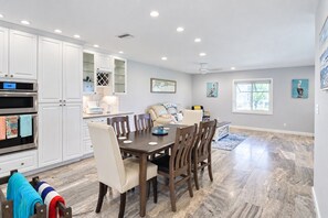 A modern kitchen with white cabinetry, a dining table with chairs, and a large window. - Longboat Key Condo with Beach Access - Pier Pressure (Longboat Key)