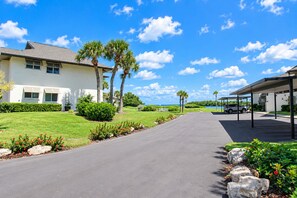 A residential street with a paved road, white houses, palm trees, and a clear blue sky. - Longboat Key Condo with Beach Access - Pier Pressure (Longboat Key)