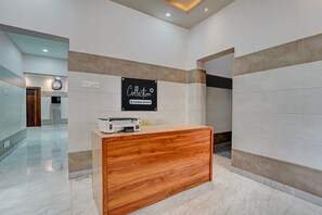 A reception desk with a sign indicating it's company-serviced, a clock, and a clean, modern interior. - Classic Puri Sea Side (Puri)