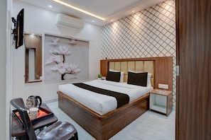 A modern bedroom with a large bed, bedside tables, a desk with a chair, and a decorative wall with a lattice pattern. - Classic Puri Sea Side (Puri)