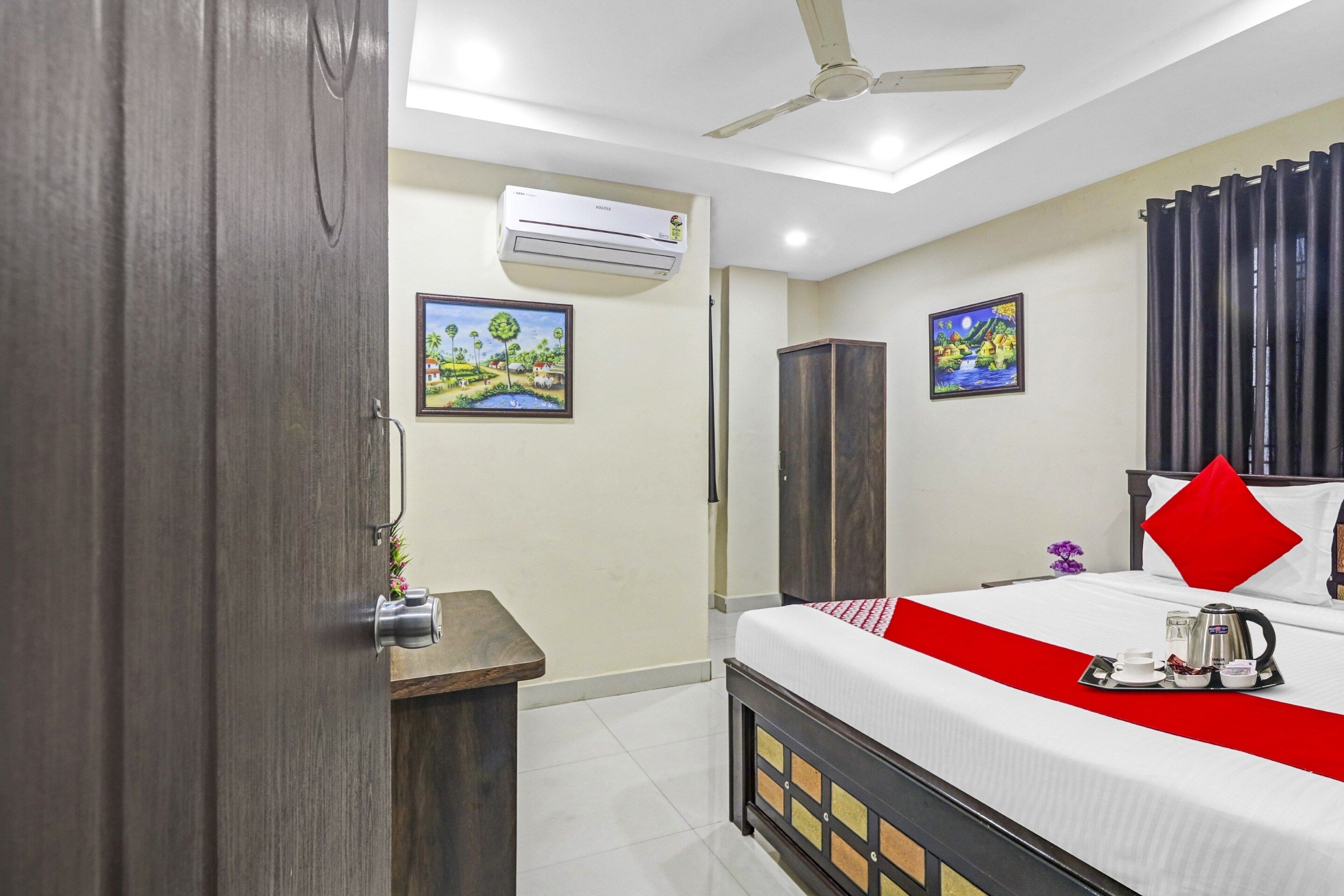 A hotel room with a bed, a wardrobe, a desk, and a ceiling fan.