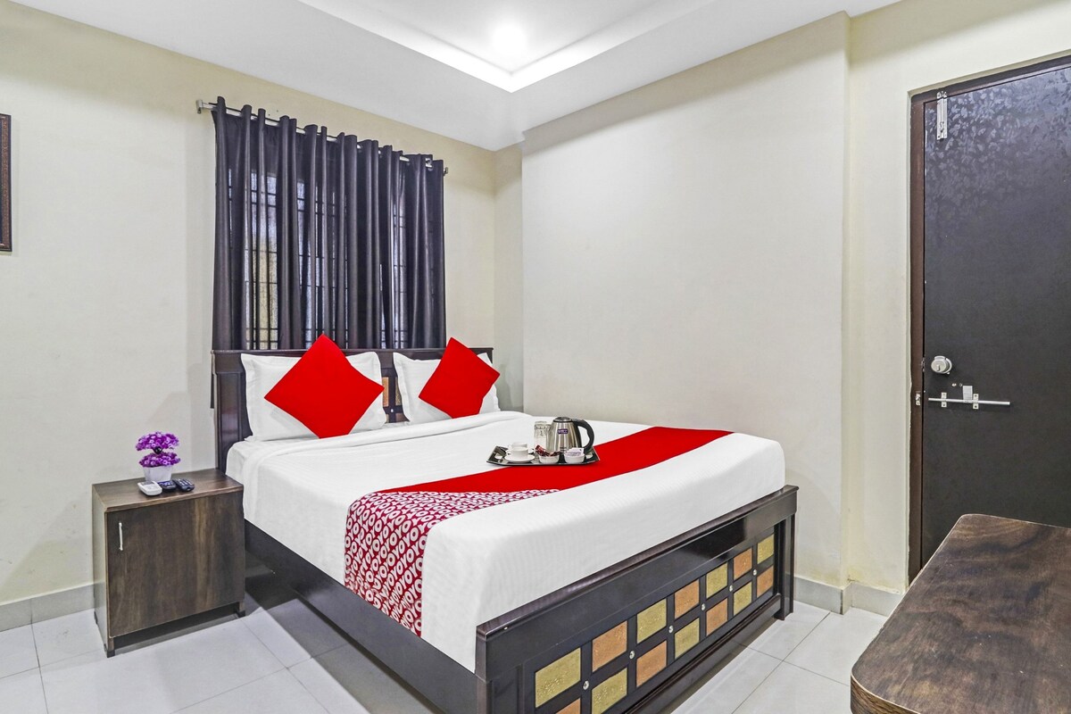 Una habitación de hotel con una cama, una mesita de noche, una puerta y una pequeña mesa.
