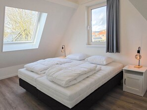 Ein Schlafzimmer mit einem Bett, zwei Nachttischen, einem Fenster und Blick auf Gebäude.