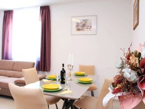 A dining area with a table set for four, a sofa, and a wall-mounted picture. - Holiday Home in Vrsi With Swimming Pool (Vrsi)