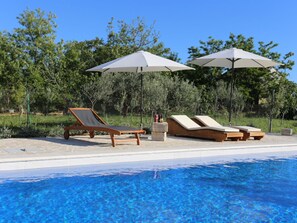 A poolside area with lounge chairs and umbrellas, surrounded by trees. - Holiday Home in Vrsi With Swimming Pool (Vrsi)