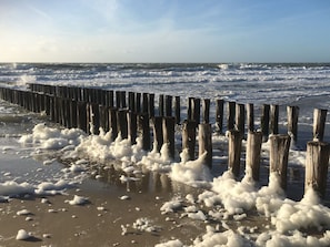 A beach with a wooden sea defense structure and waves crashing onto the shore. - We01 Het Kantoor (Westkapelle)