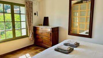 A bedroom with a bed, a dresser, a mirror, and a window with curtains.