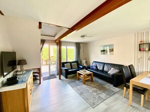 Ein Wohnzimmer mit Sofa, Couchtisch, Fernseher und einem Essbereich mit Tisch und Stühlen.