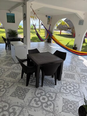 A covered patio area with a dining table and chairs, a refrigerator, and a hammock. - Beach Getaway in El Zapote - 3BR Home with AC (El Zapote)