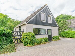 Ein eingeschossiges Haus mit Satteldach, einer Haustür und einer kleinen Veranda.