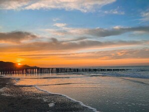 Ein Küsten-Sonnenuntergang mit einem sich ins Wasser erstreckenden Steg.