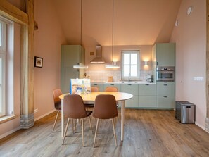 A modern kitchen with a dining area, wooden flooring, and pendant lighting. - Holiday Home With 2 Bedrooms (Den Hoorn)